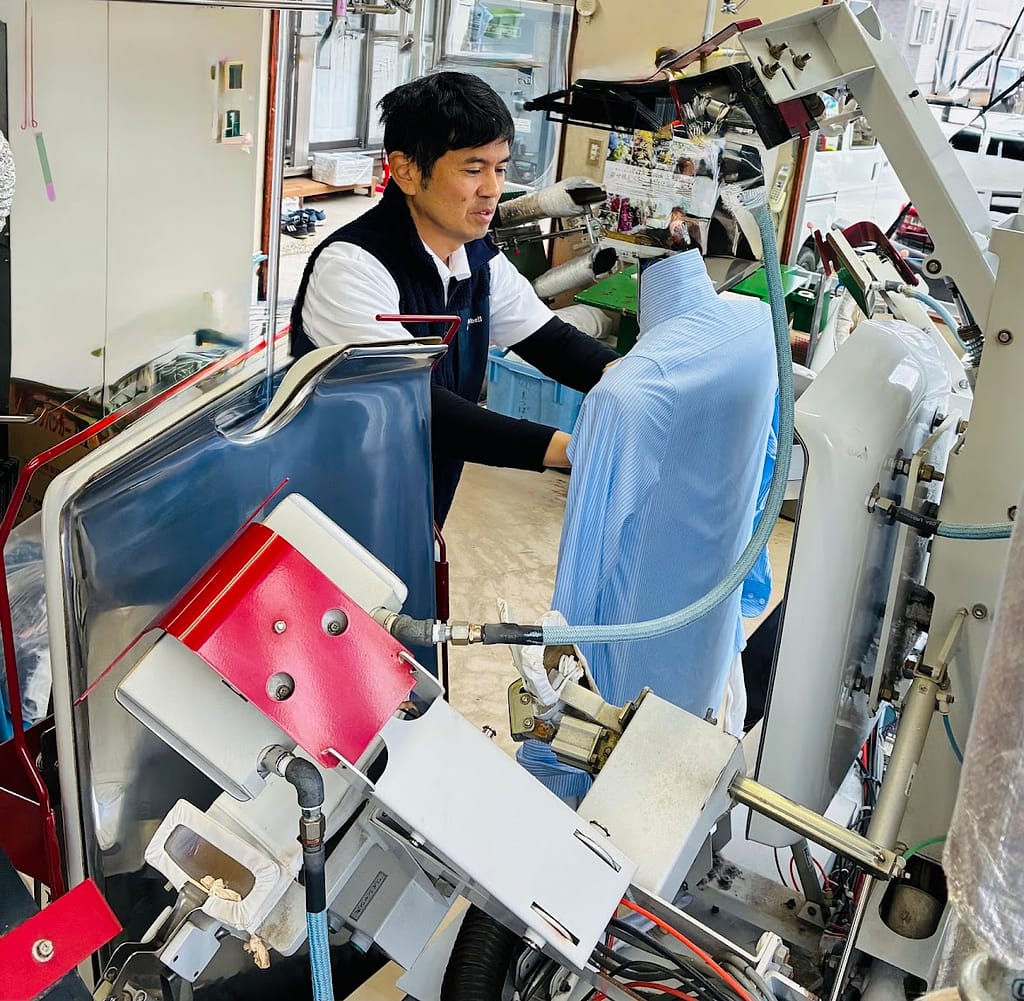 クリーニングアンジェの店長が店内で仕上げ作業を行う様子