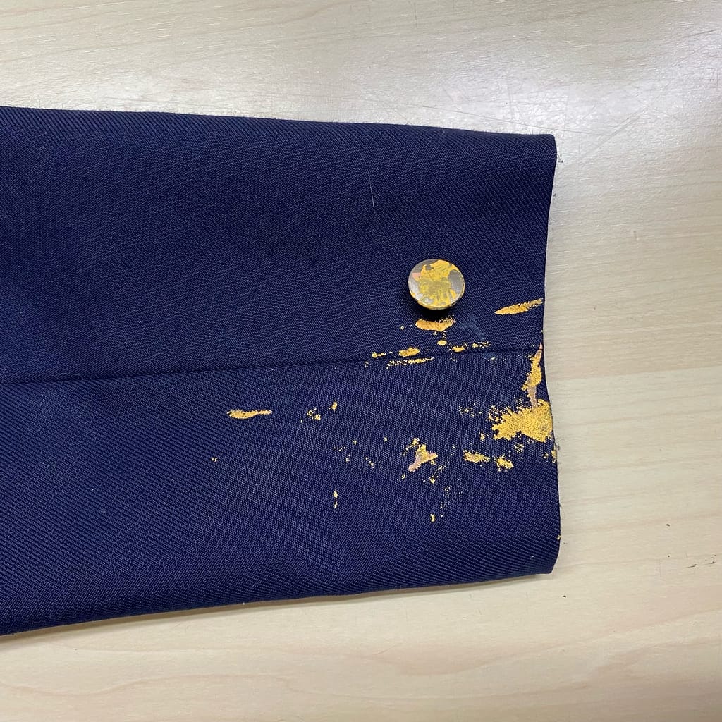 ペンキ汚れが付着した制服袖口のクリーニング前の状態
