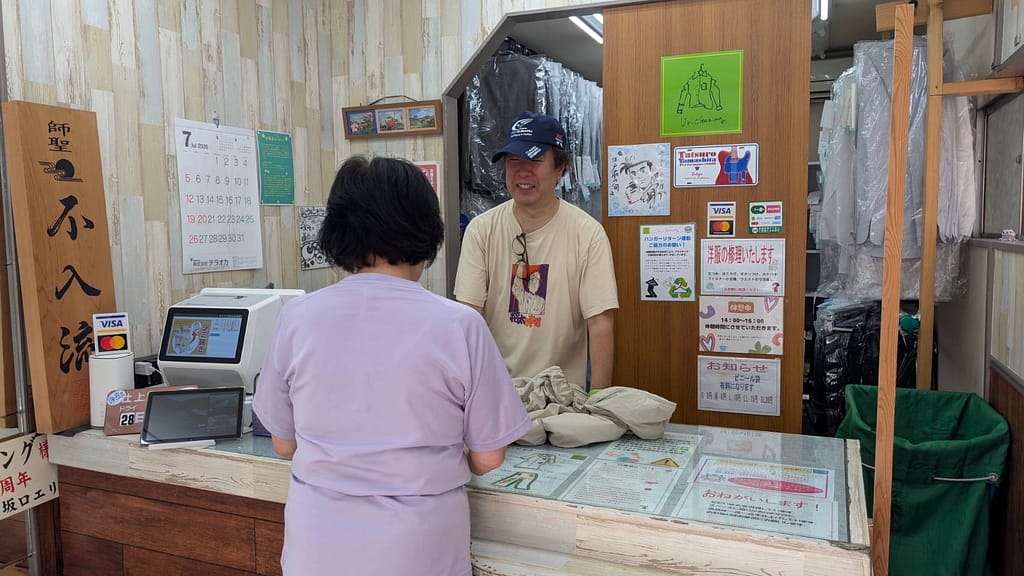 クリーニング店でネクタイや衣類について相談する様子 写真提供:ユニクリーニング中町店