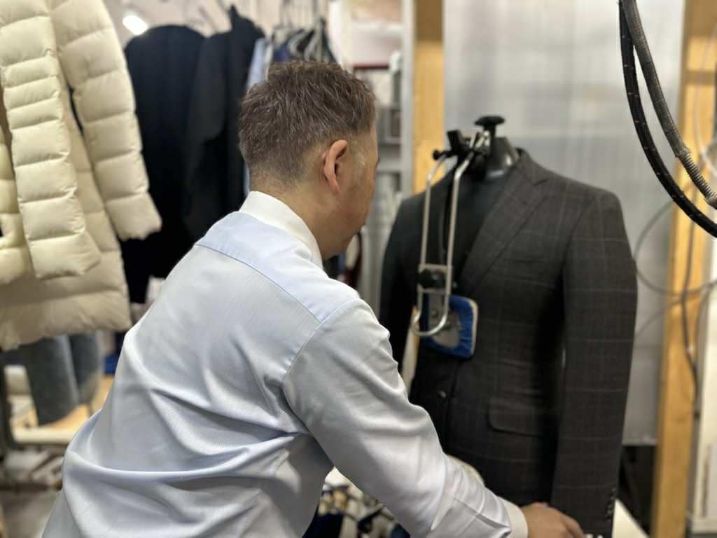 札幌のファッションクリーニングSuzuki.で、店主がスーツの仕上げ作業を行っている様子。立体プレス機を使った丁寧な作業風景。