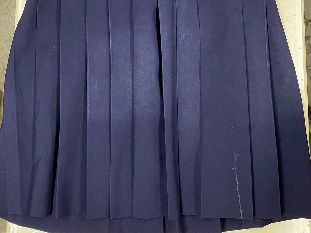 プリーツが乱れ染み、テカリのひどい学生スカートのクリーニング前の状態