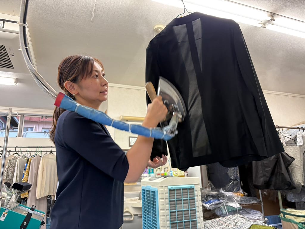 大竹クリーニング店で衣類を仕上げるスタッフ