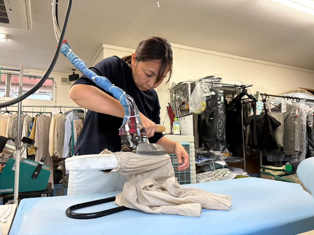 大竹クリーニング店で衣類をアイロン仕上げするスタッフ
