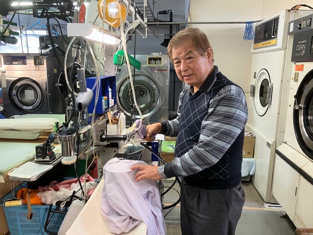 湯川クリーニング店主による衣類の仕上げ作業