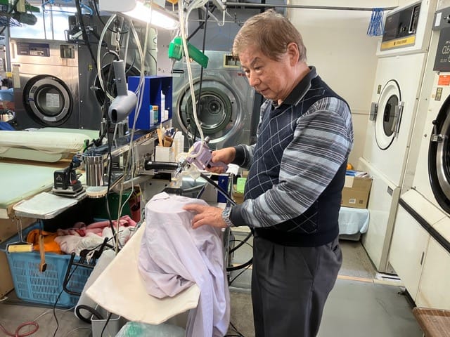 衣類の状態を確認しながら作業する湯川クリーニング店主