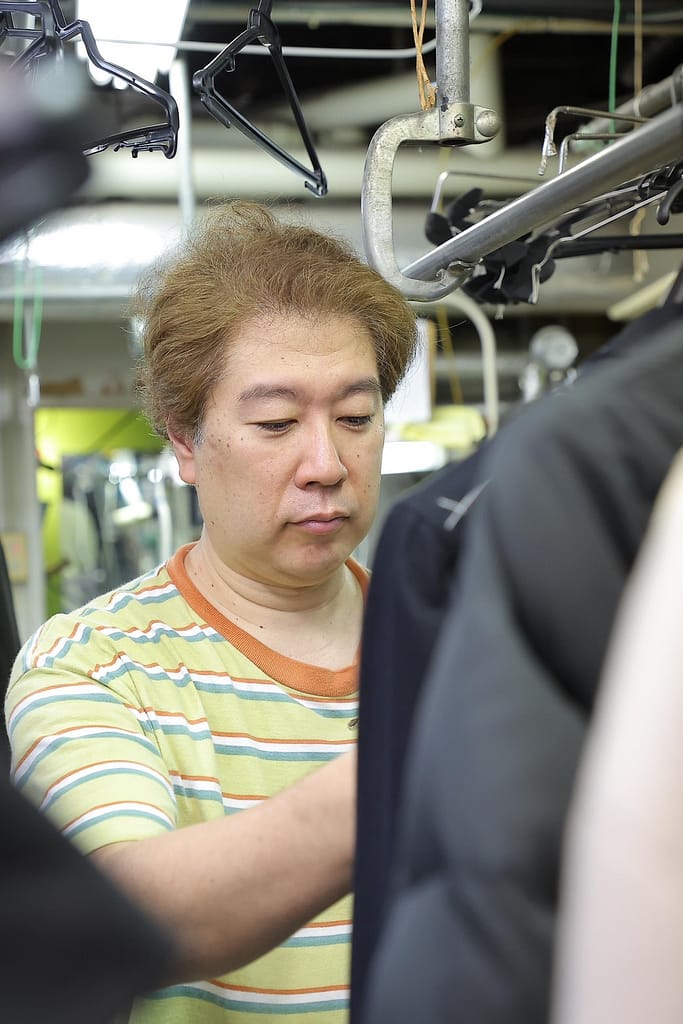 クリーニング前に衣類を確認するユニクリーニング(目黒区)の店主
