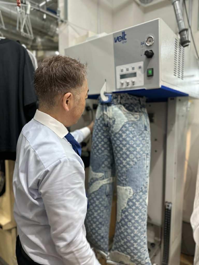 ファッションクリーニングSuzuki.の店内で、専用機械を使ってズボンのプレス仕上げを行う作業風景。