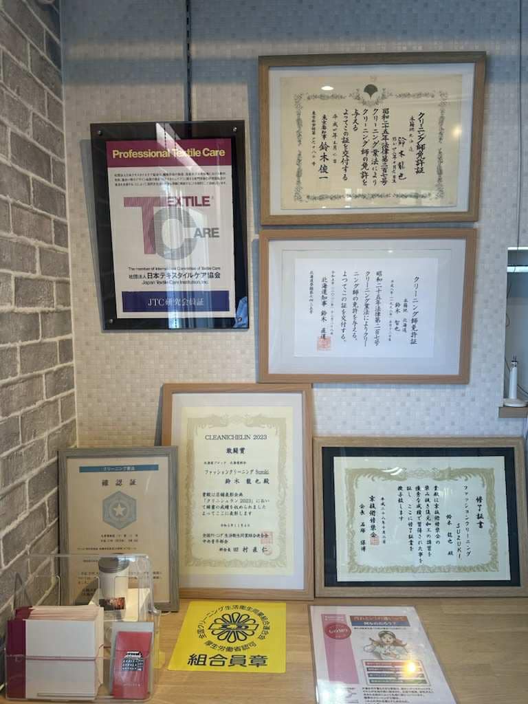 クリーニング技術に関する表彰状や認定証が並ぶ店内の様子。
