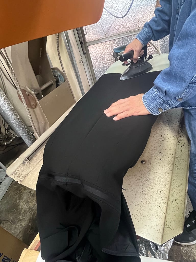 松野クリーニング本店でスタッフがジャケットを丁寧にプレス仕上げしている様子