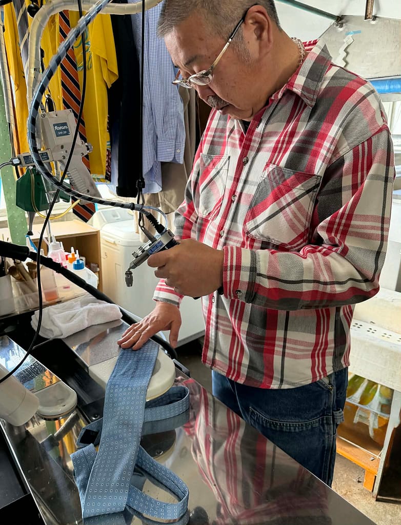 ネクタイのしみ抜き作業を行う店主