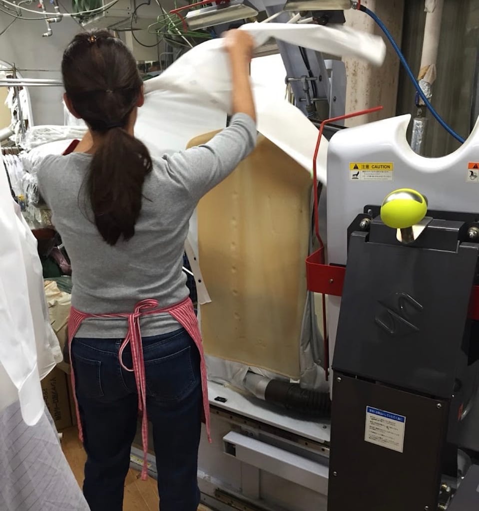 クリーニング五香 本店で衣類を仕上げる女性スタッフ