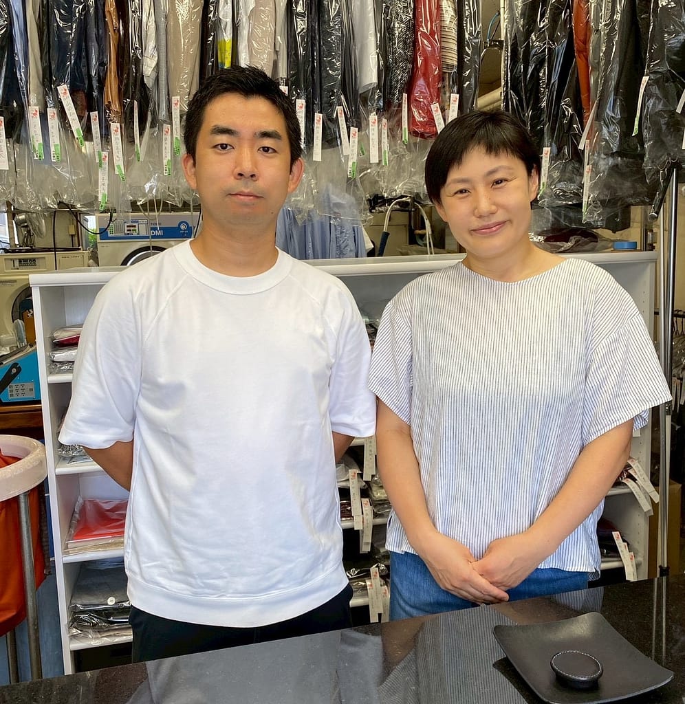 受付カウンターに立つクリーニングコマツの店主と奥様(東京都大田区)